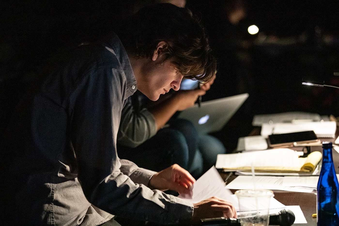 Side profile shot of Alex Timbers working in a dimly lit room