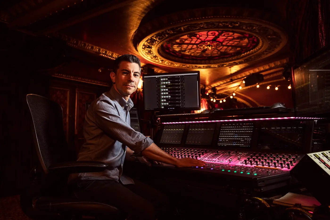 Peter Hylenski, sound designer of Moulin Rouge! The Musical sitting at a sound board inside the theatre