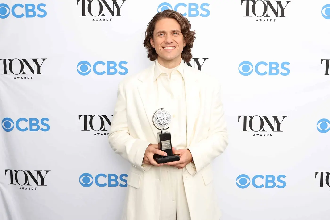 Aaron Tveit holding his Tony Award for Moulin Rouge! The Musical on the red carpet
