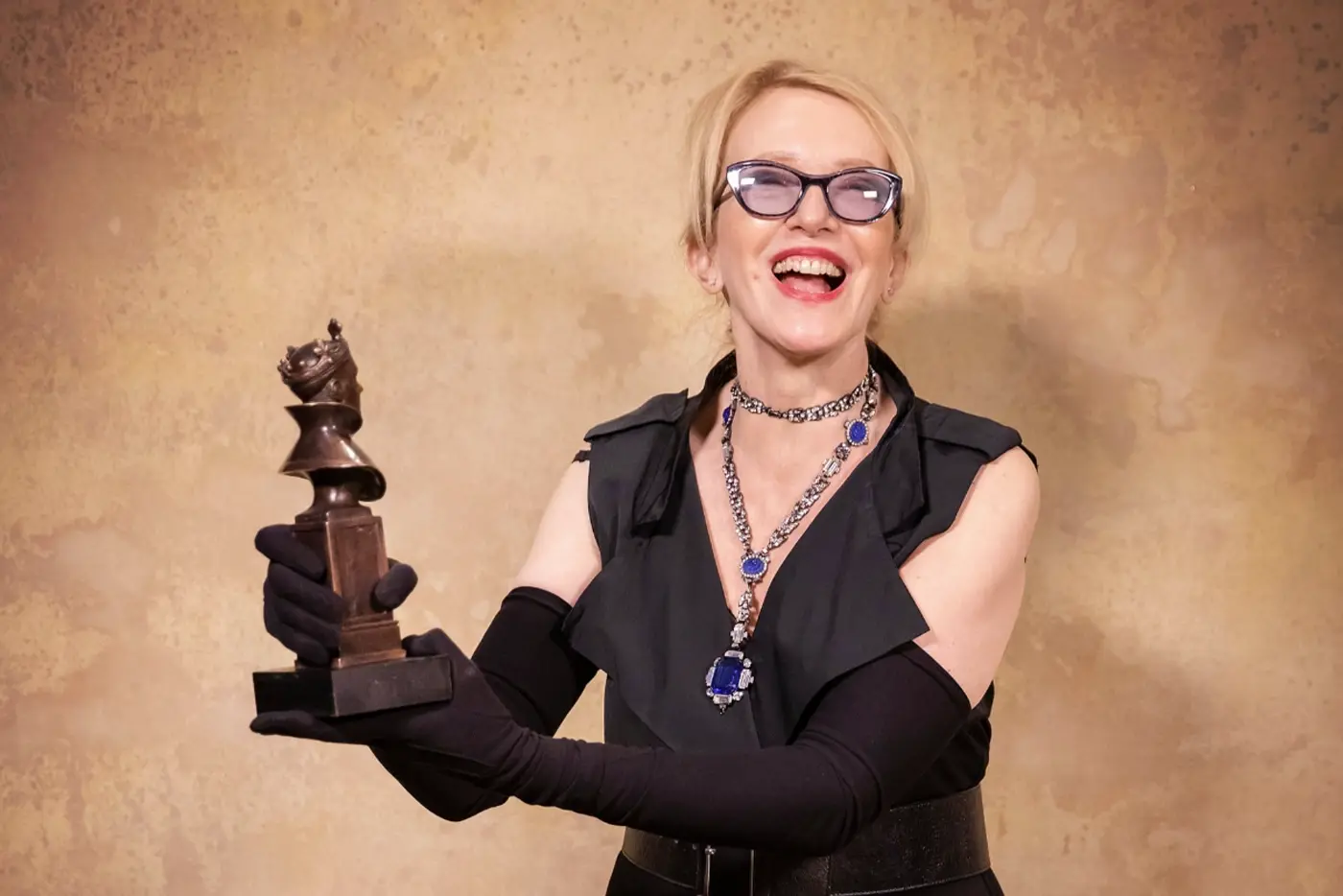 Catherine Zuber holding up her Olivier Award for Moulin Rouge! The Musical