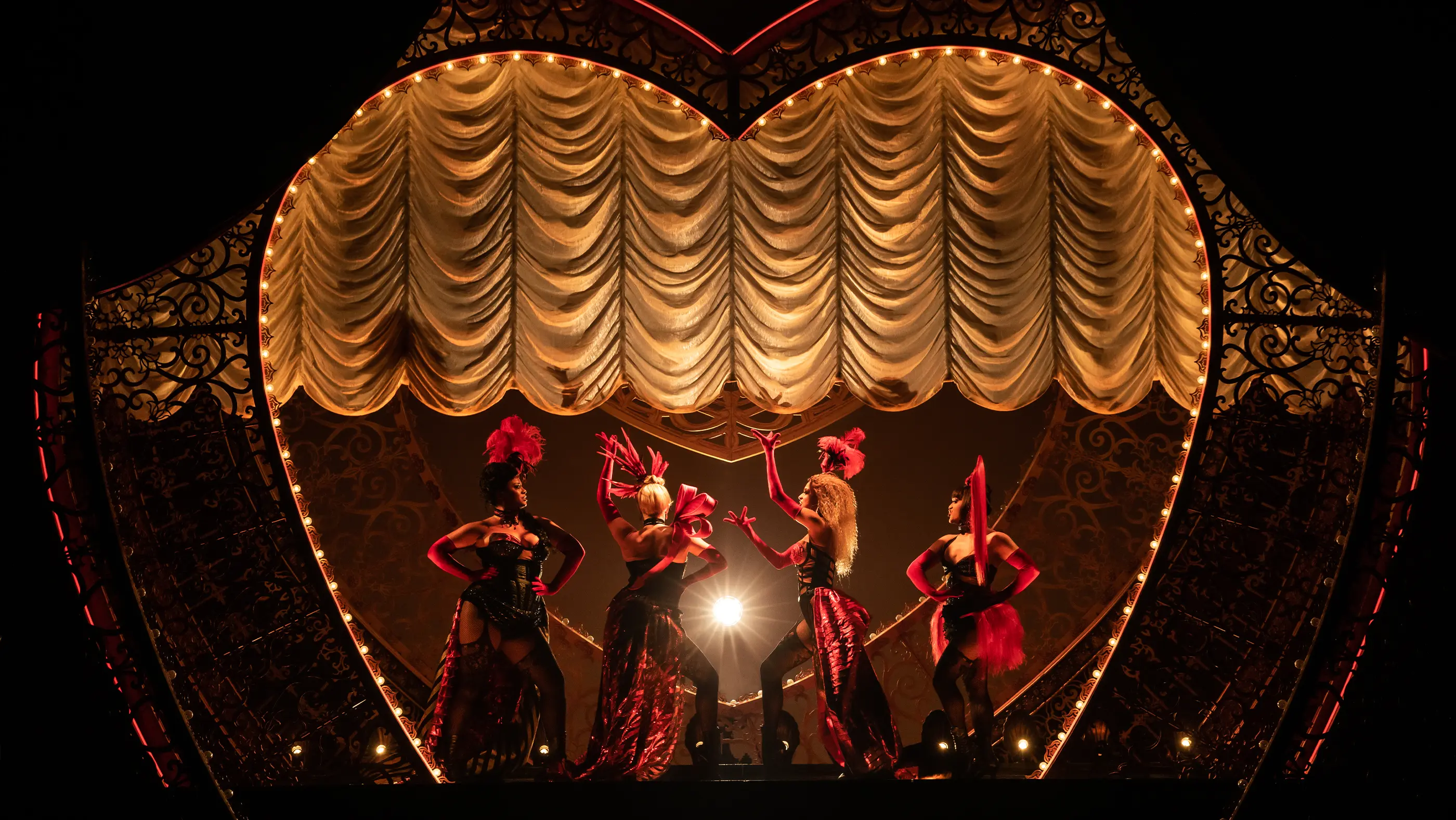 Scene from Moulin Rouge! The Musical featuring the four Lady Ms lined up on stage as the curtain rises.