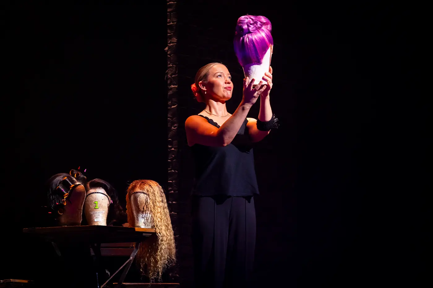 A crew member showing off a wig on stage during 'Get Technical! Behind the Curtain of Moulin Rouge! The Musical' on the West End.