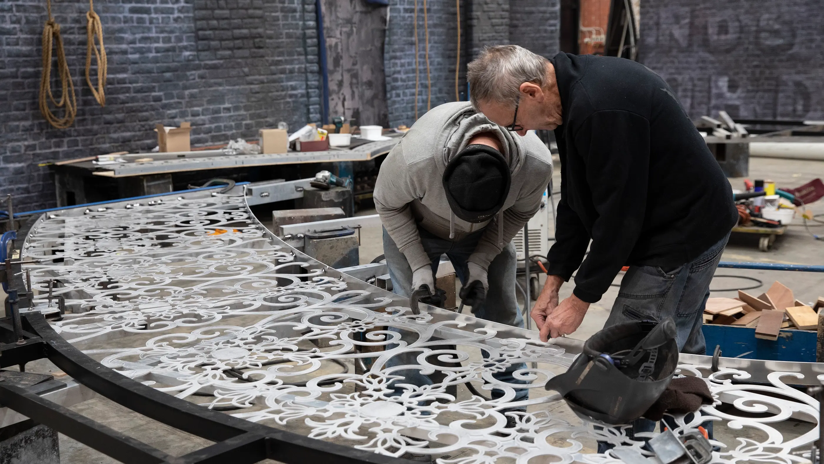 Two people applying the finishing touches to one of the heart portal set pieces from Moulin Rouge! The Musical. Other set pieces can be seen behind them in the workshop.