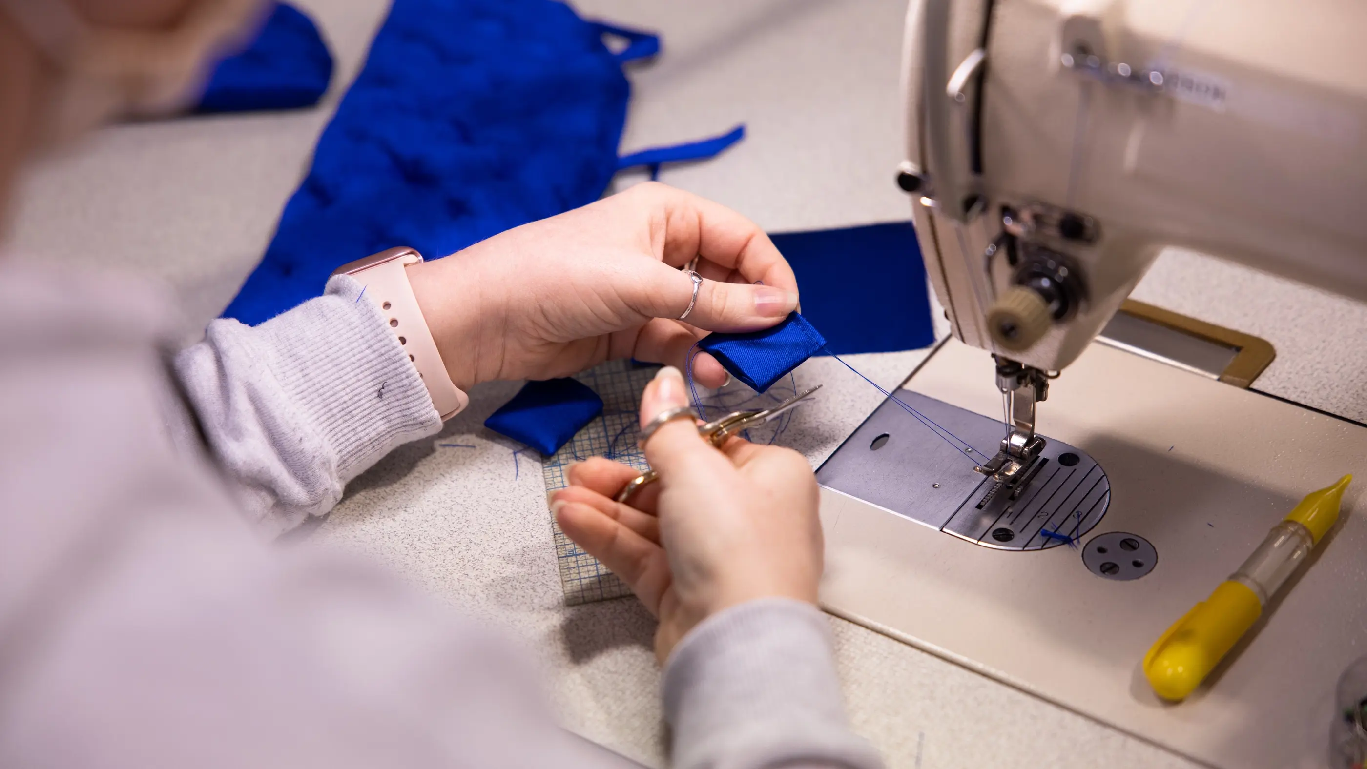A close-up shot of a person's hands as they sew a costume piece from Elephant Love Medley in Moulin Rouge! The Musical
