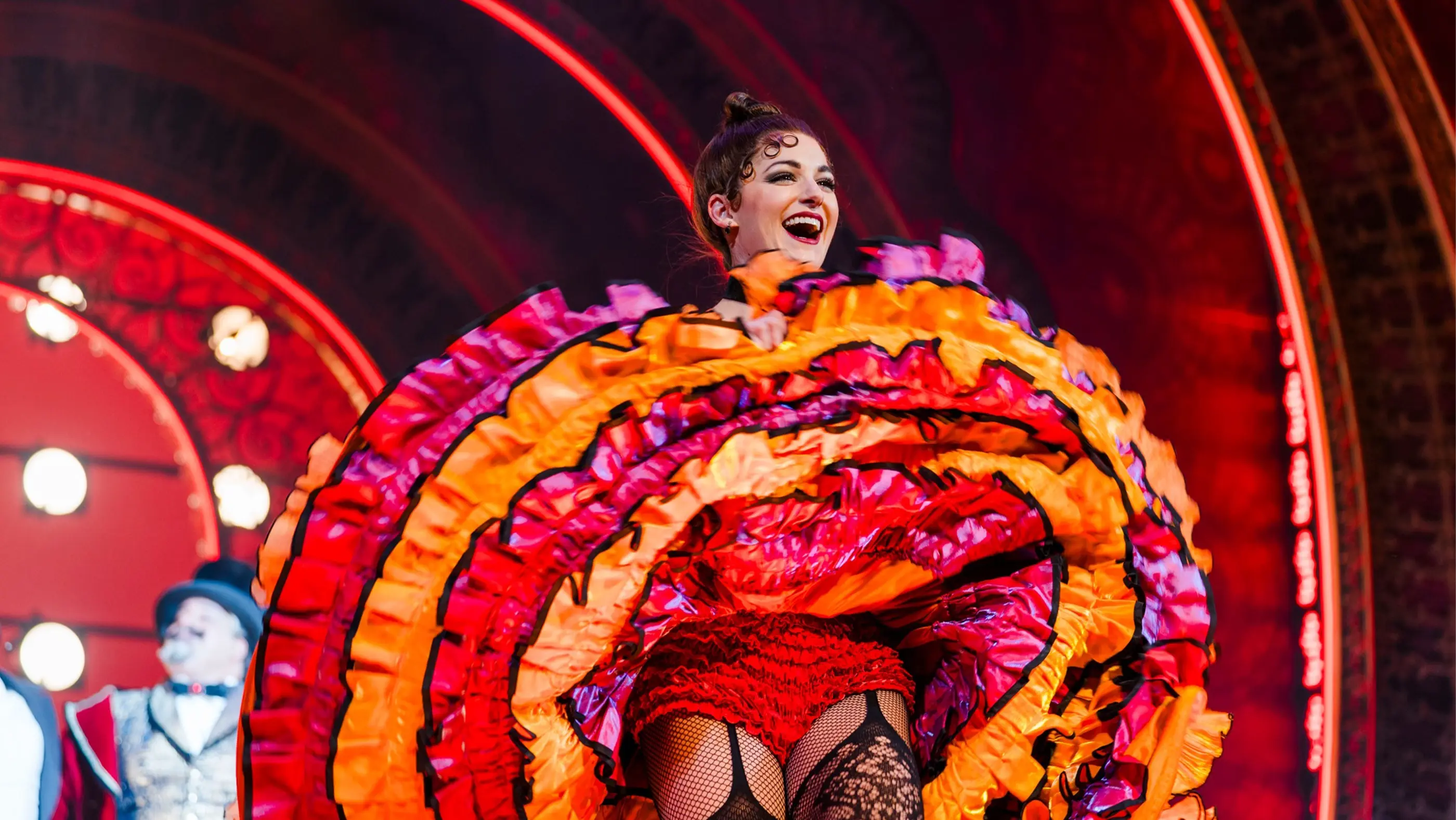 An ensemble cast member in Moulin Rouge! The Musical showing off the intricate, colourful detailing of her can-can skirt during the curtain call at the end of the show.