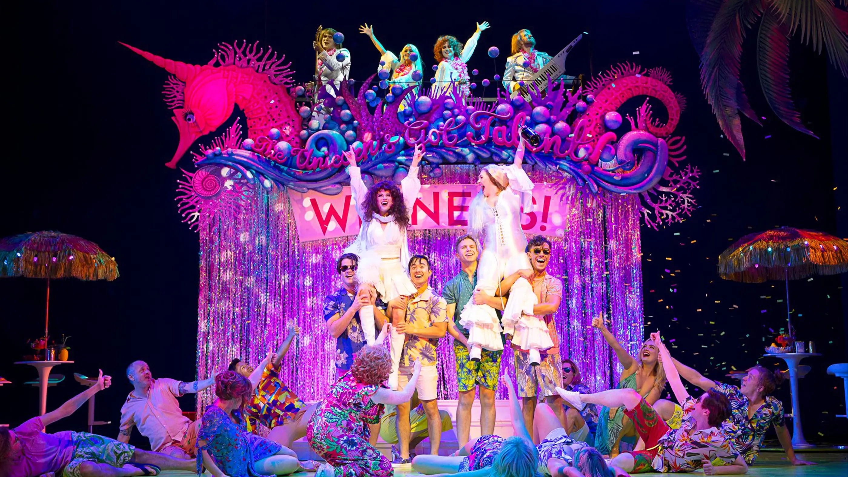 Muriel and Rhonda lifted into the air by a pair of guys each in their ABBA costumes with a crowd around them