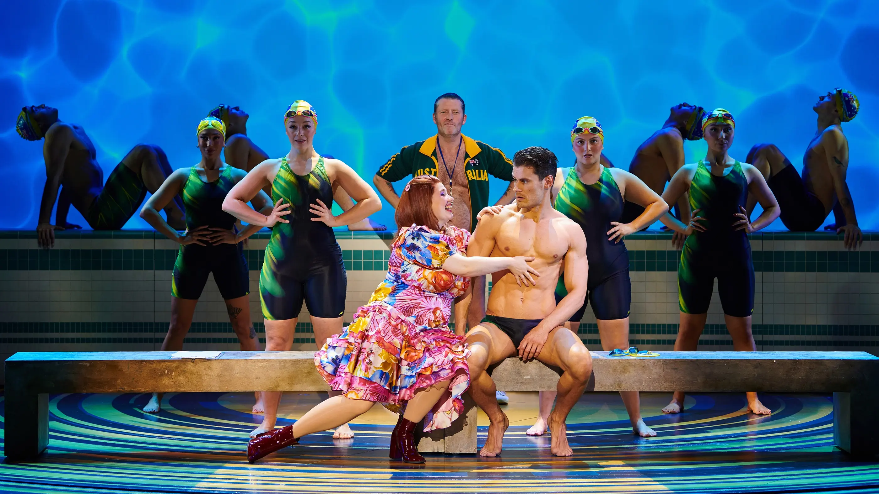 Muriel sitting next to a man in his bathing suit. In front of an Australian swimming team.
