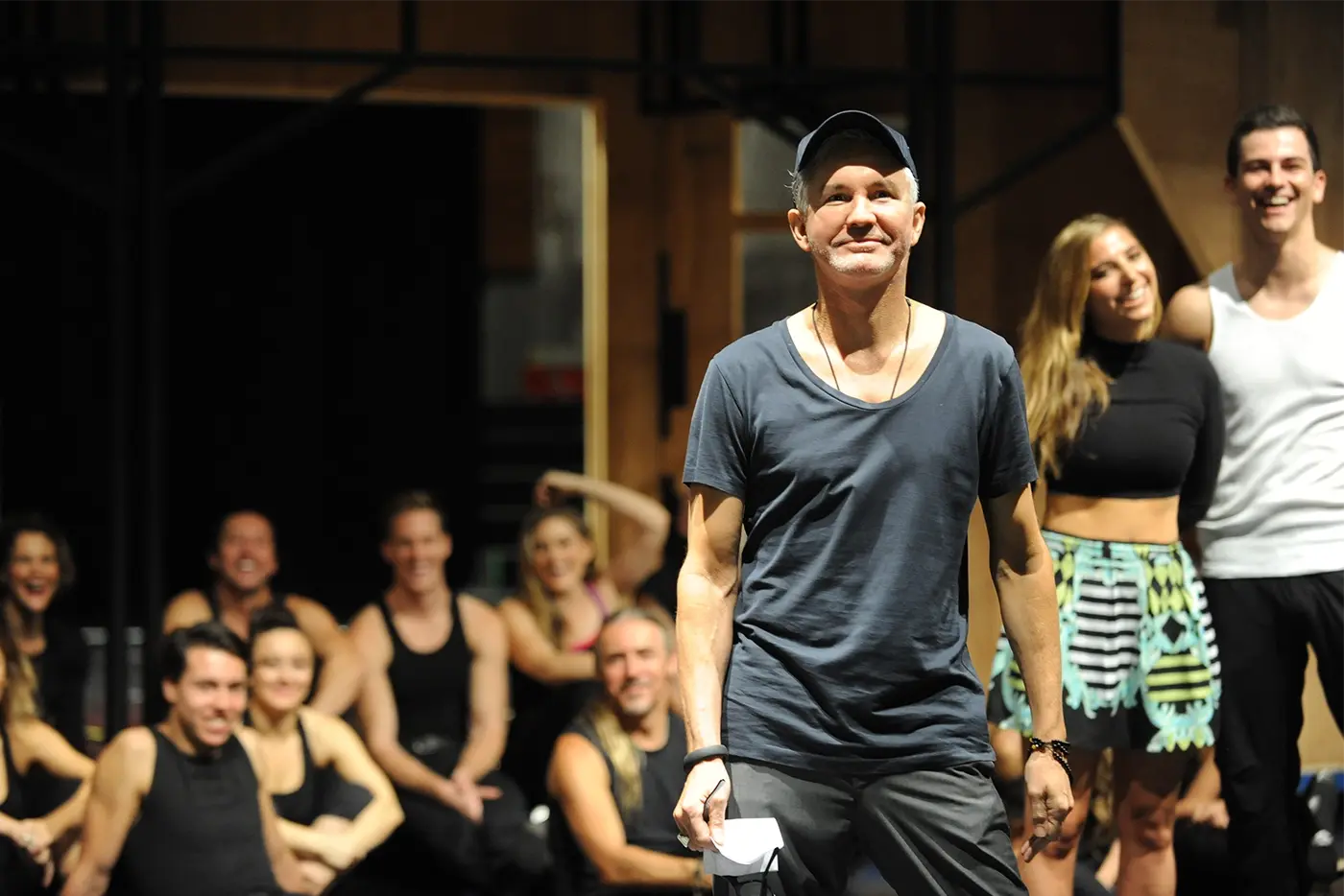 Baz Lurhmann in the foreground with the cast at a rehearsal in the background