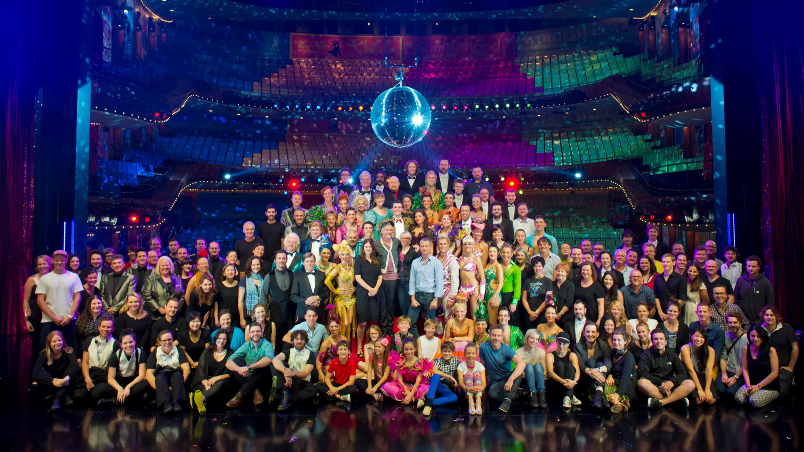 Whole company photo with the theatre in the background under the big disco ball