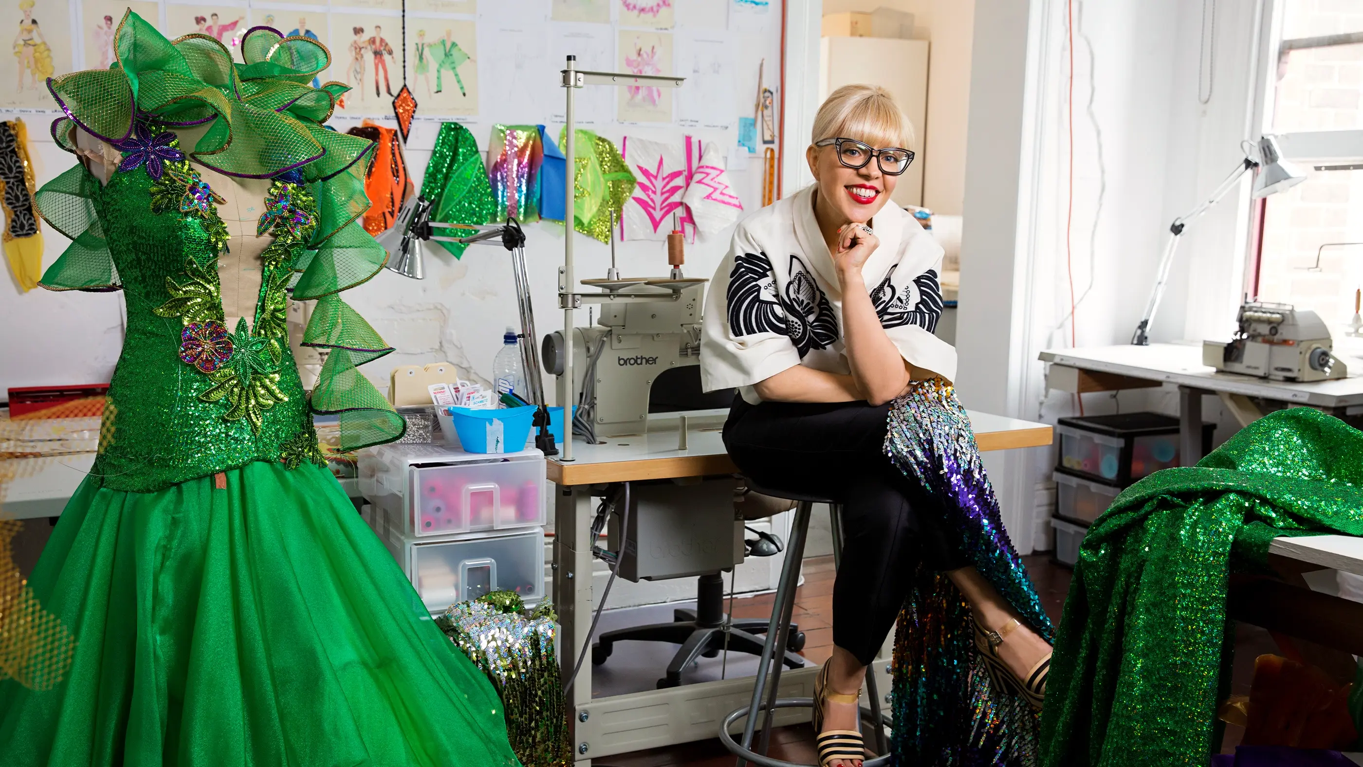 Catherine Martin in a costume studio beside a green sequin gown