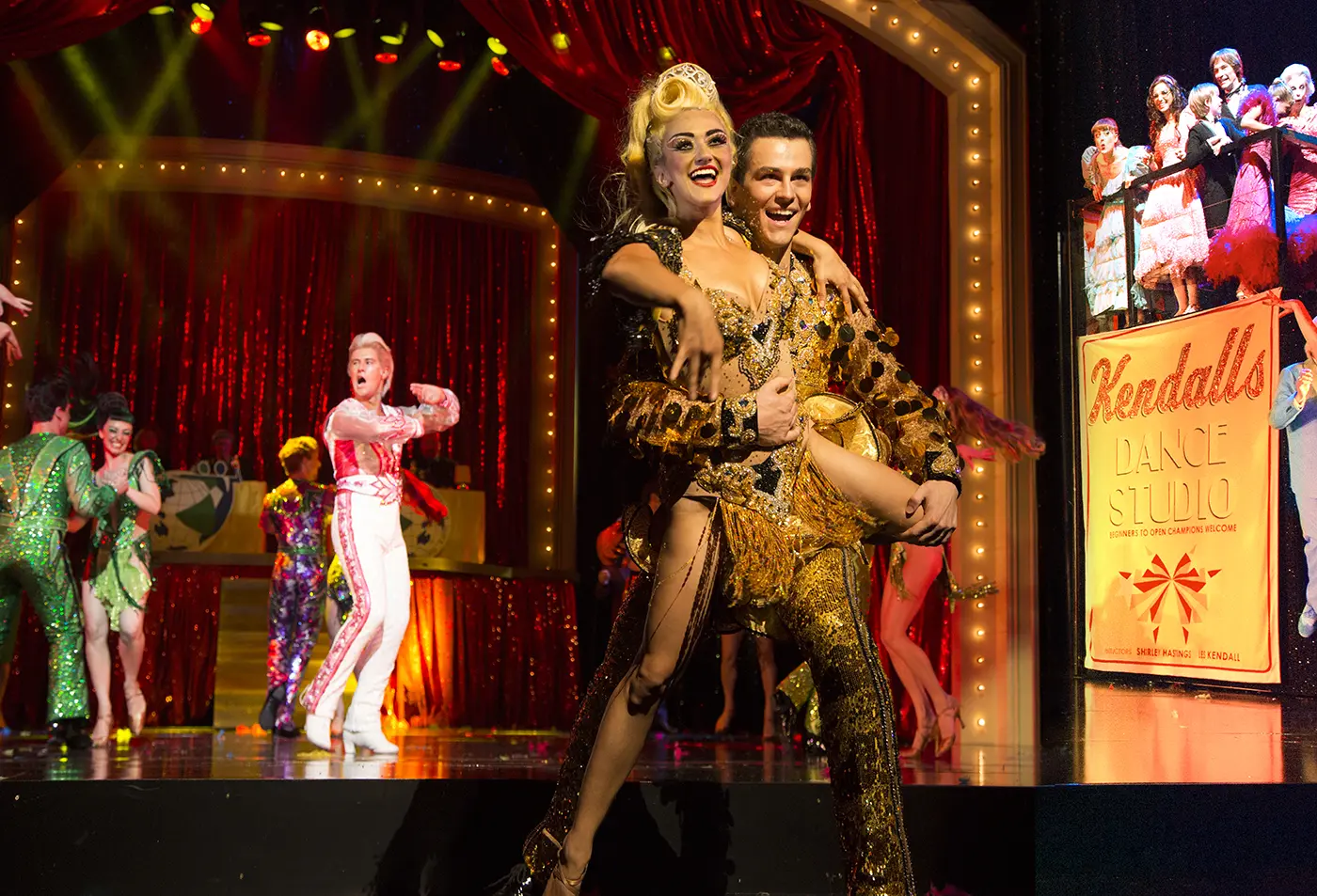 2 dancers in gold sequin matching costumes in the foreground at Kendalls Dance Studio