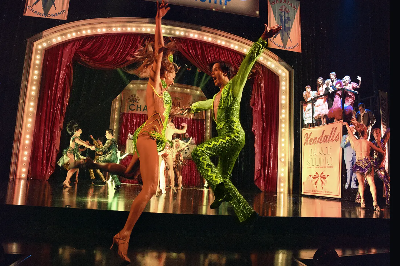 2 dancers in green sequin matching costumes in the foreground at Kendalls Dance Studio