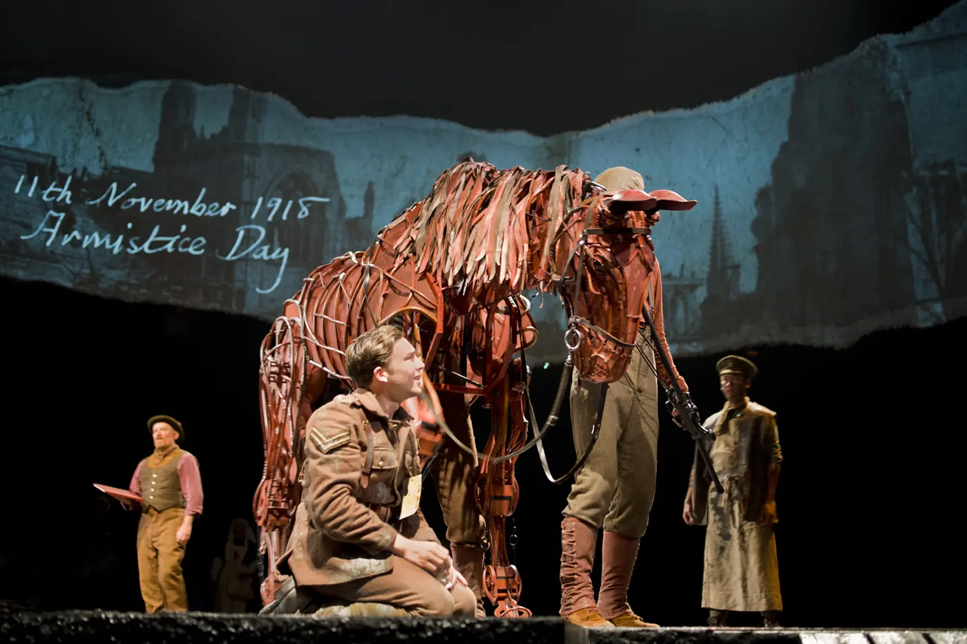 Actors manipulating horse puppets during a dramatic moment in War Horse.
