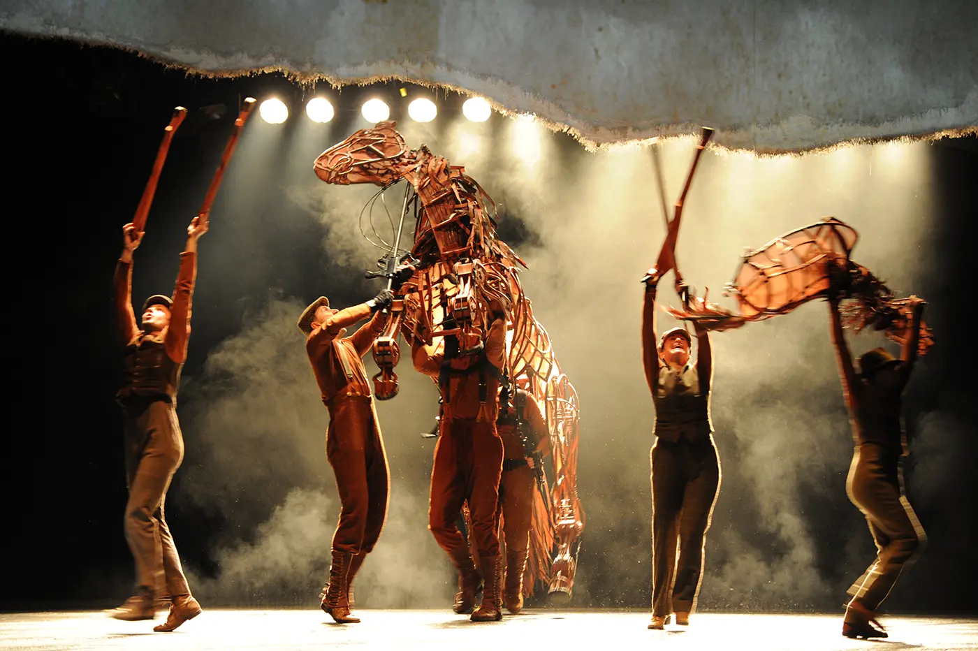 Life-sized horse puppets on stage with actors performing in War Horse play.