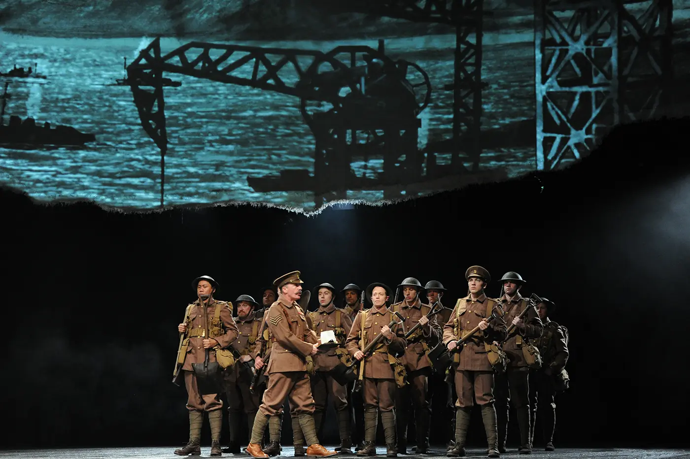 Stage scene from War Horse showing ensemble cast in military attire.