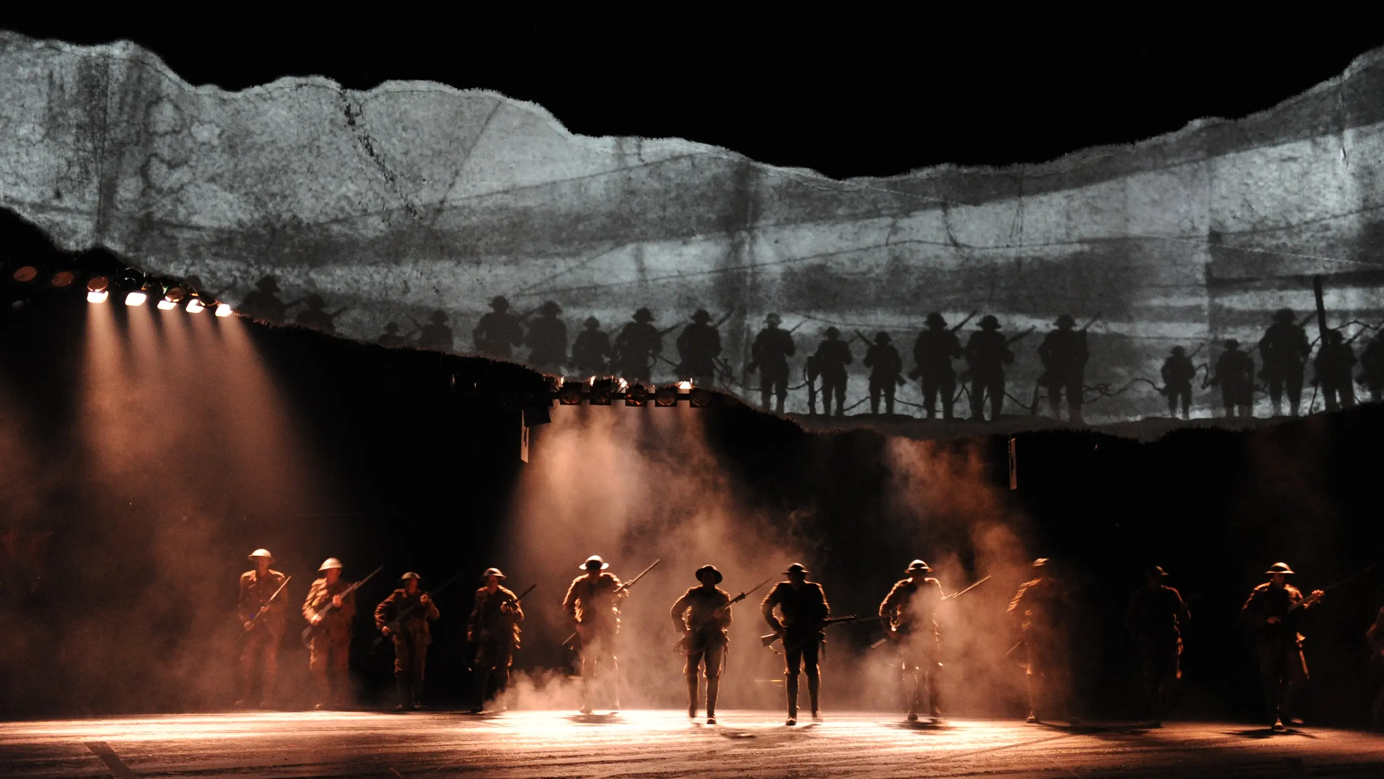 A scene from the War Horse play in Australia with men's silhouettes lined up in in a row. They are wearing military outfits and holding guns.