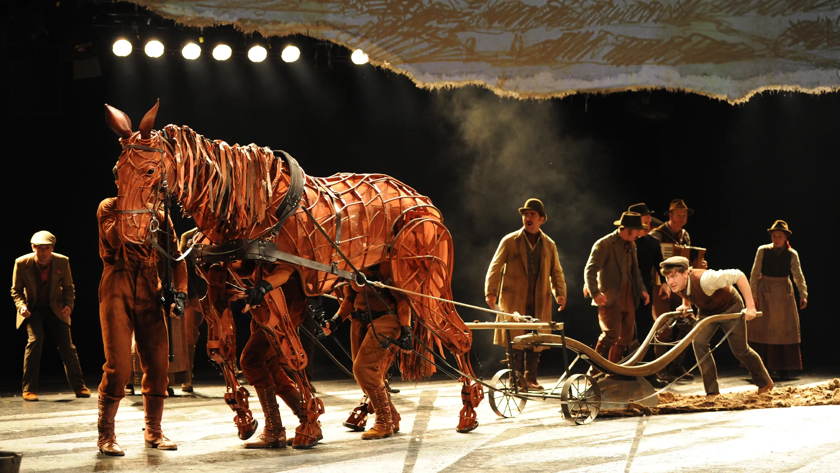 A plough being drawn by a life-sized horse puppet on stage in War Horse play.