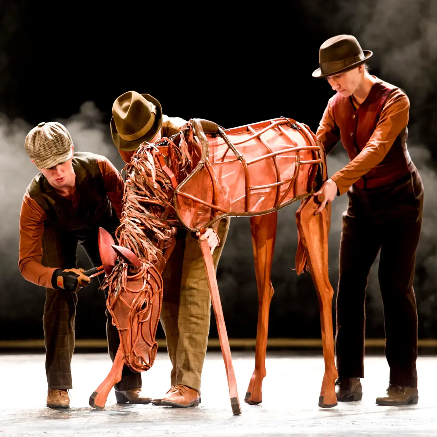 Foal puppet on stage with three young actors performing in War Horse play.