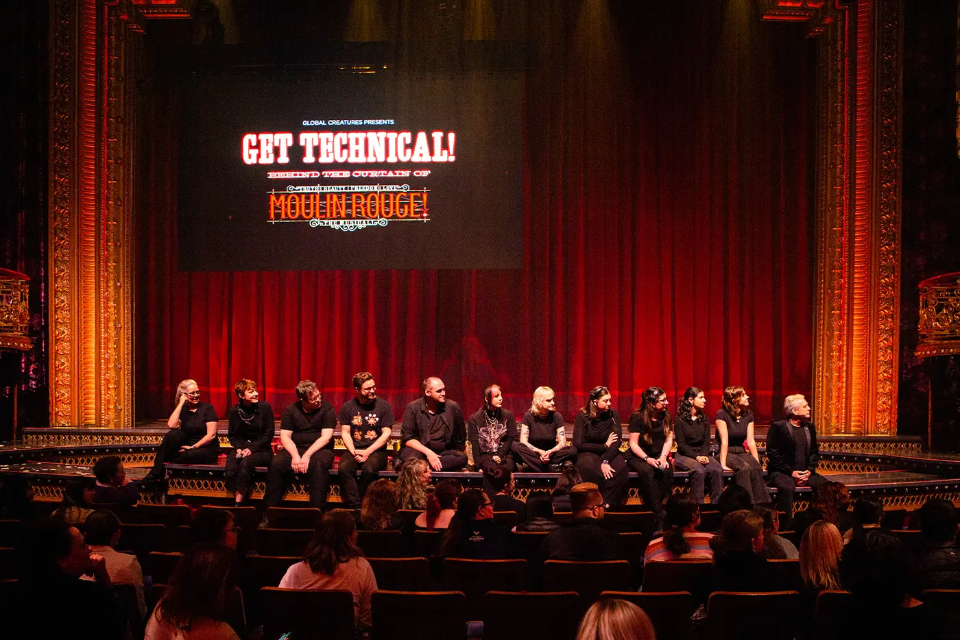 The crew of Moulin Rouge! The Musical sitting along the edge of the stage in all black-clothing during question time at 'Get Technical! Behind The Curtain of Moulin Rouge! The Musical'
